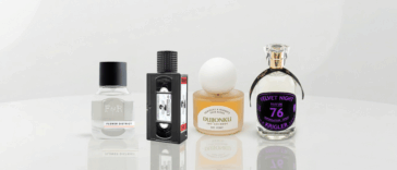 A banner-style photograph featuring four unique perfume bottles arranged on a glossy white reflective table. From left to right: Fulton & Roark, Xyrena, KST Scent, and Krigler.