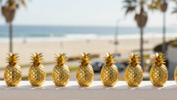 Golden Pineapple trinkets lined up on balcony rail.